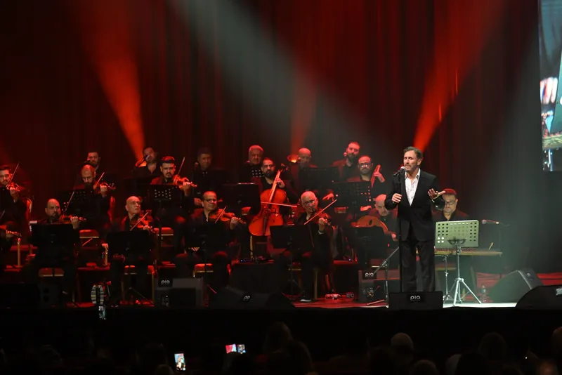 Kadim Al Sahir and the orchestra under red and green stage lights